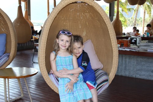 Isabelle and Oliver in the swinging bar seats by the beach.