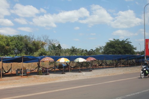 A rest area on the side of the road with hammocks for sleeping.  Another photo taken from our moving car!