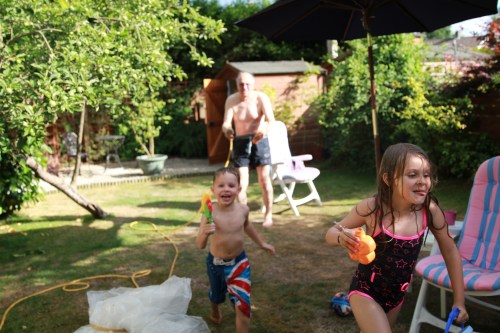 Grandad soaking the kids in the garden.