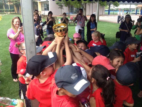 As many hands as possible trying to raise the cup for winning the Sports Day cup for their house.  Li House won the day for Infants!